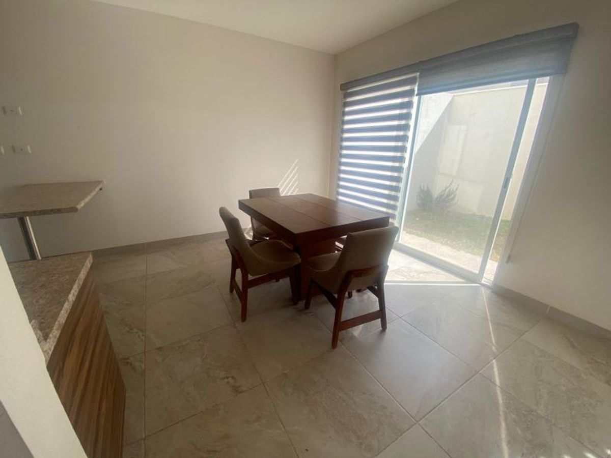 Mesa de comedor con sillas, piso cerámico claro y puerta corrediza hacia el patio
