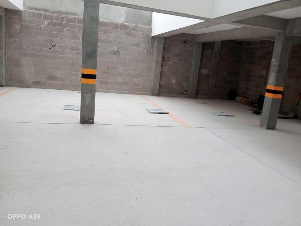 Estacionamiento cubierto con piso de concreto, columnas con franjas de seguridad y cajones numerados