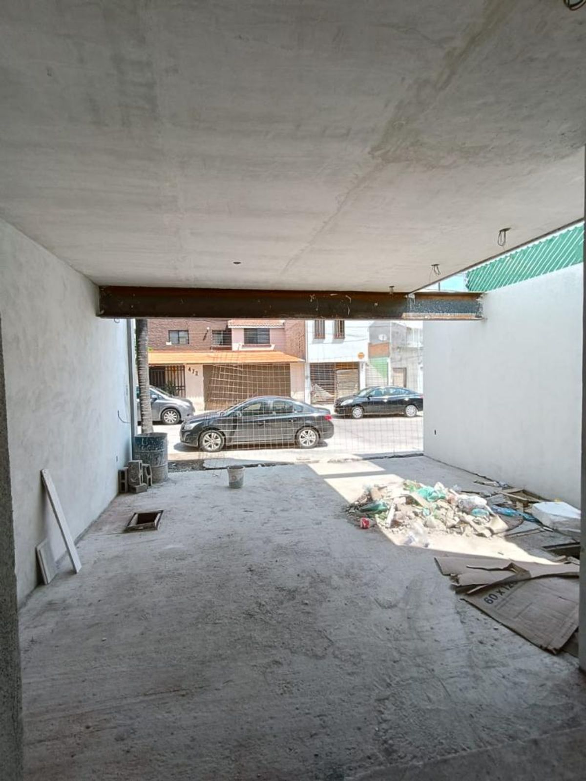 Cochera en construcción con piso de concreto, viga metálica y vista a la calle