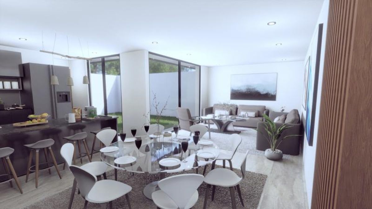 Comedor con mesa redonda de cristal, cocina con barra y sala de estar integrada