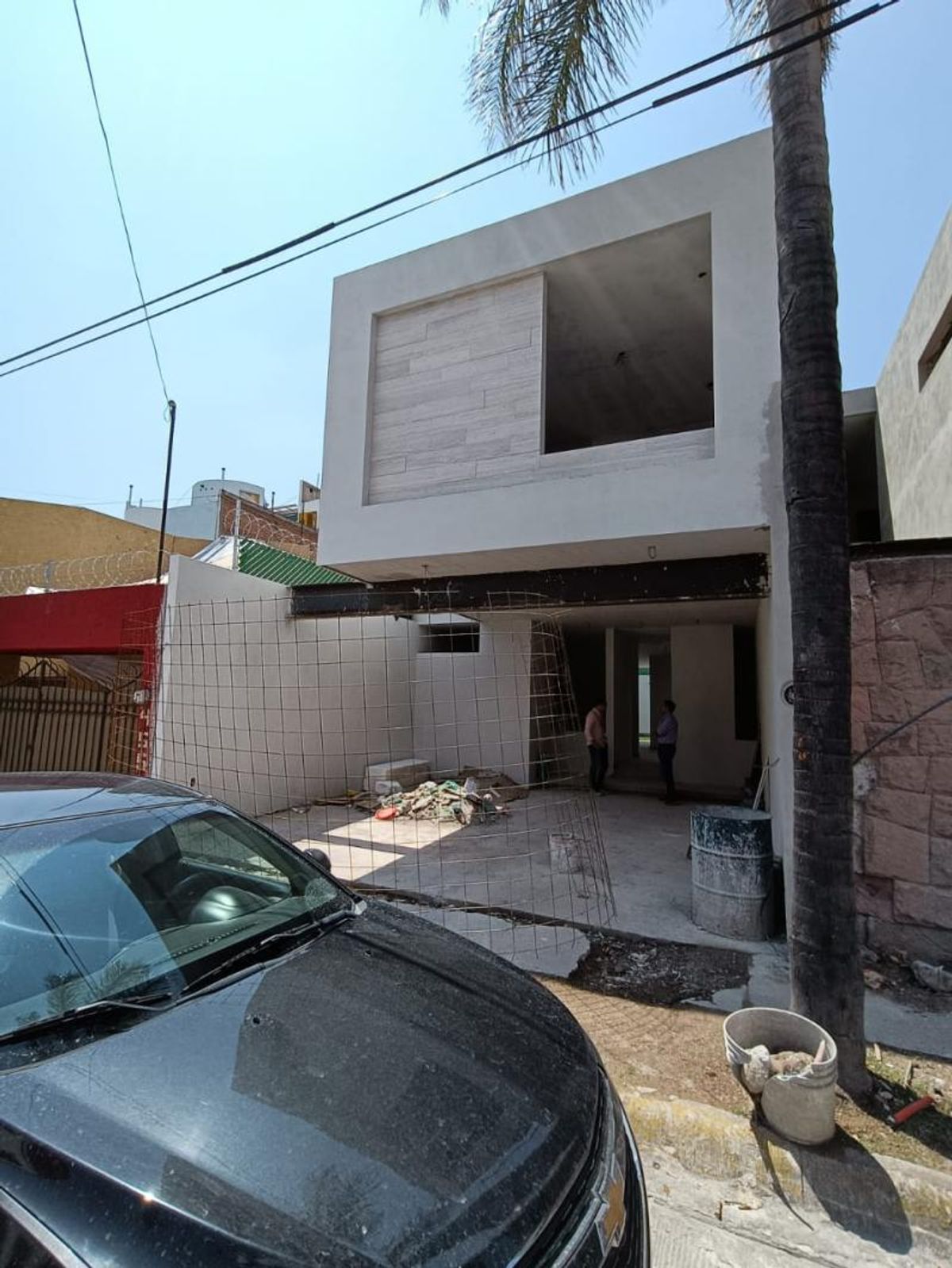 Fachada de dos niveles en construcción con muros blancos, panel texturizado y viga metálica