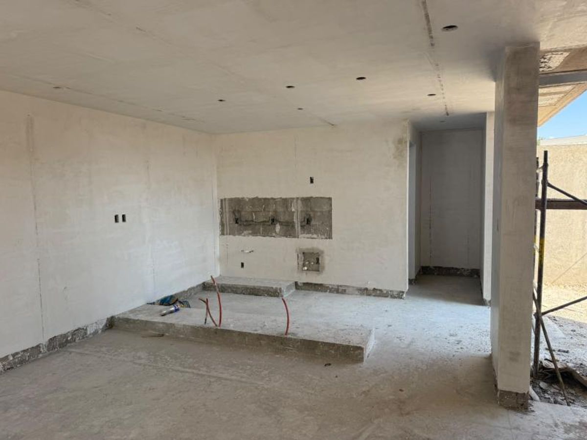 Espacio interior en construcción con muros enyesados, piso de concreto e instalaciones eléctricas expuestas