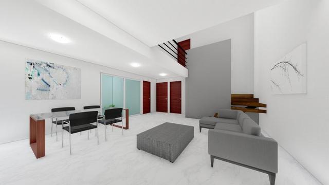 Sala y comedor de doble altura con sofás grises y mesa con sillas negras
