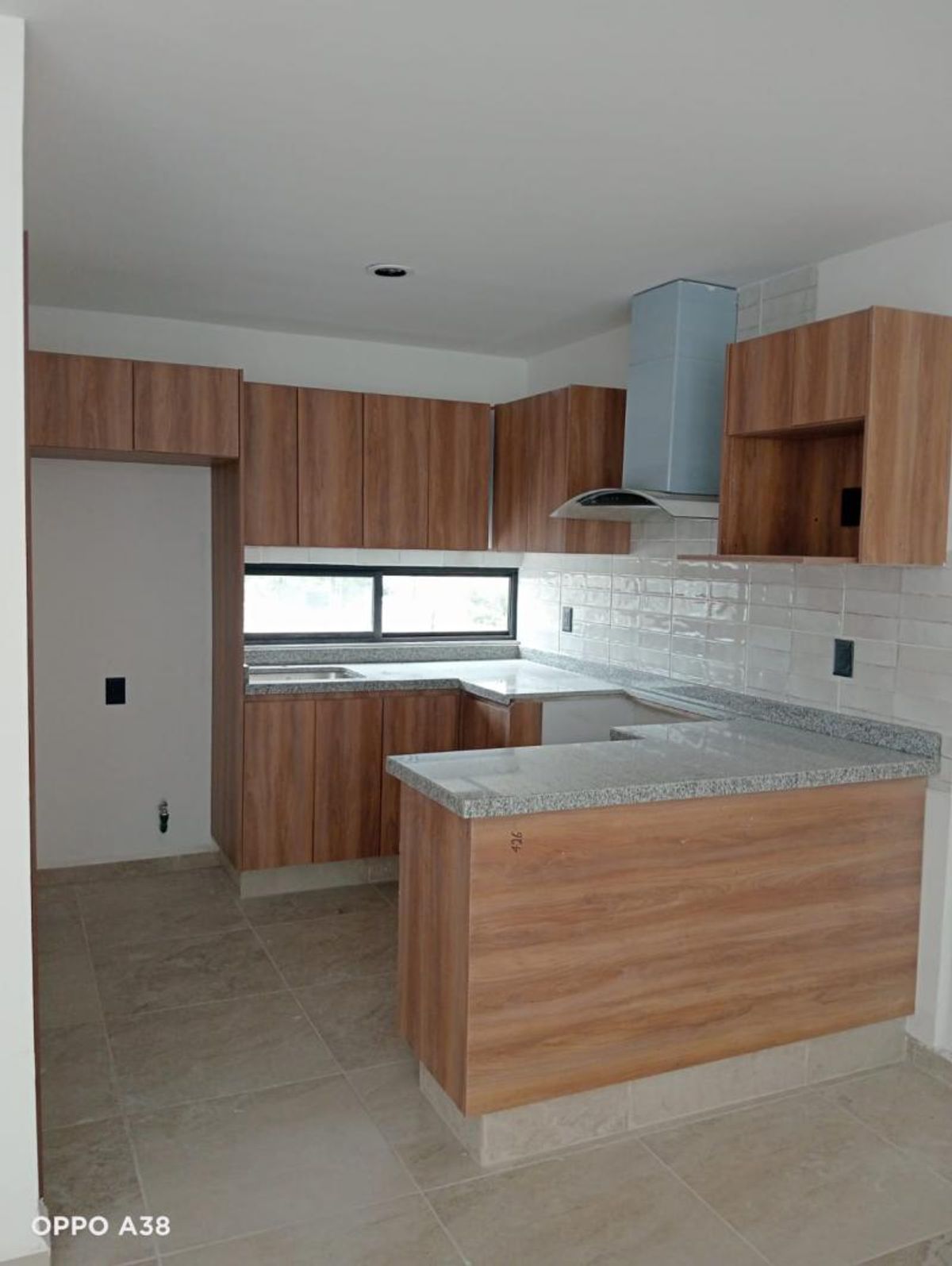 Cocina integral con barra, gabinetes de madera, cubierta de granito gris y campana extractora