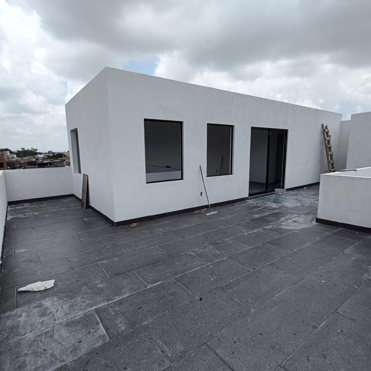 Terraza en azotea con piso de loseta gris y paredes blancas con ventanas negras