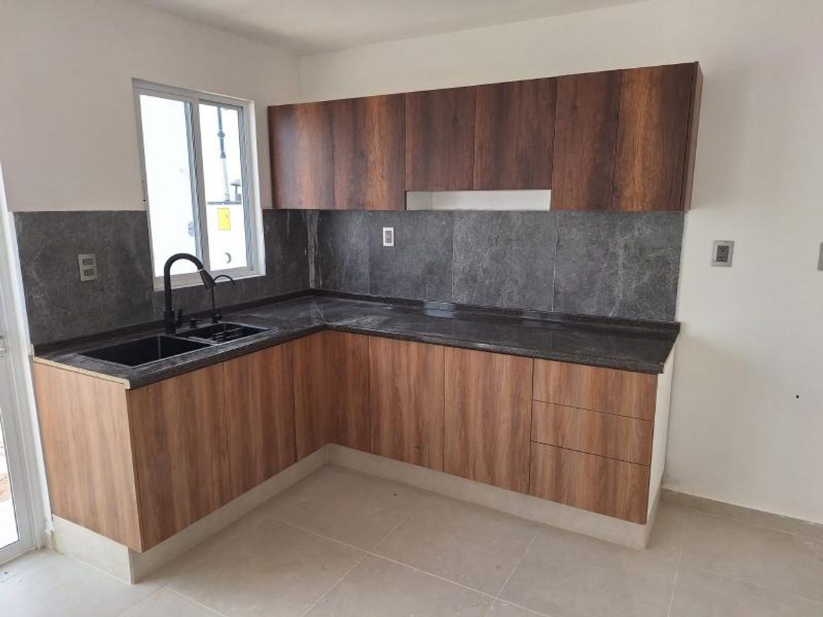 Cocina integral con gabinetes de madera, cubierta de granito oscuro, fregadero negro y ventana