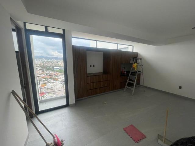 Espacio de loft con mueble de madera empotrado, piso gris y ventanal con vista urbana