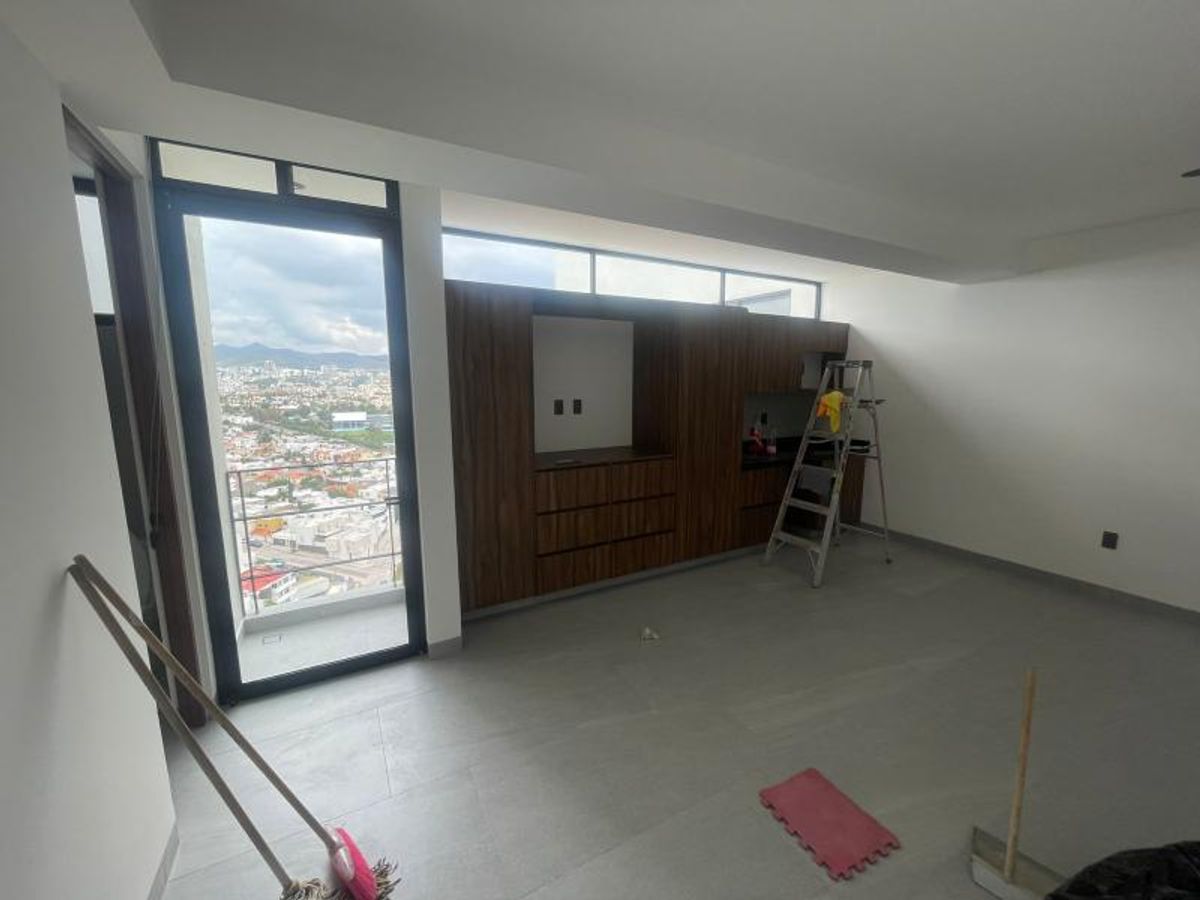 Espacio de loft con mueble de madera empotrado, piso gris y ventanal con vista urbana