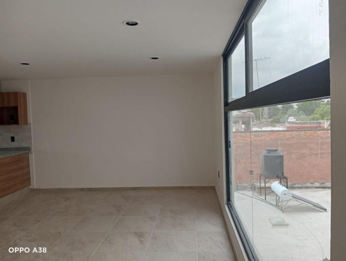 Interior vacío con piso de loseta, luces empotradas y ventanal hacia la terraza