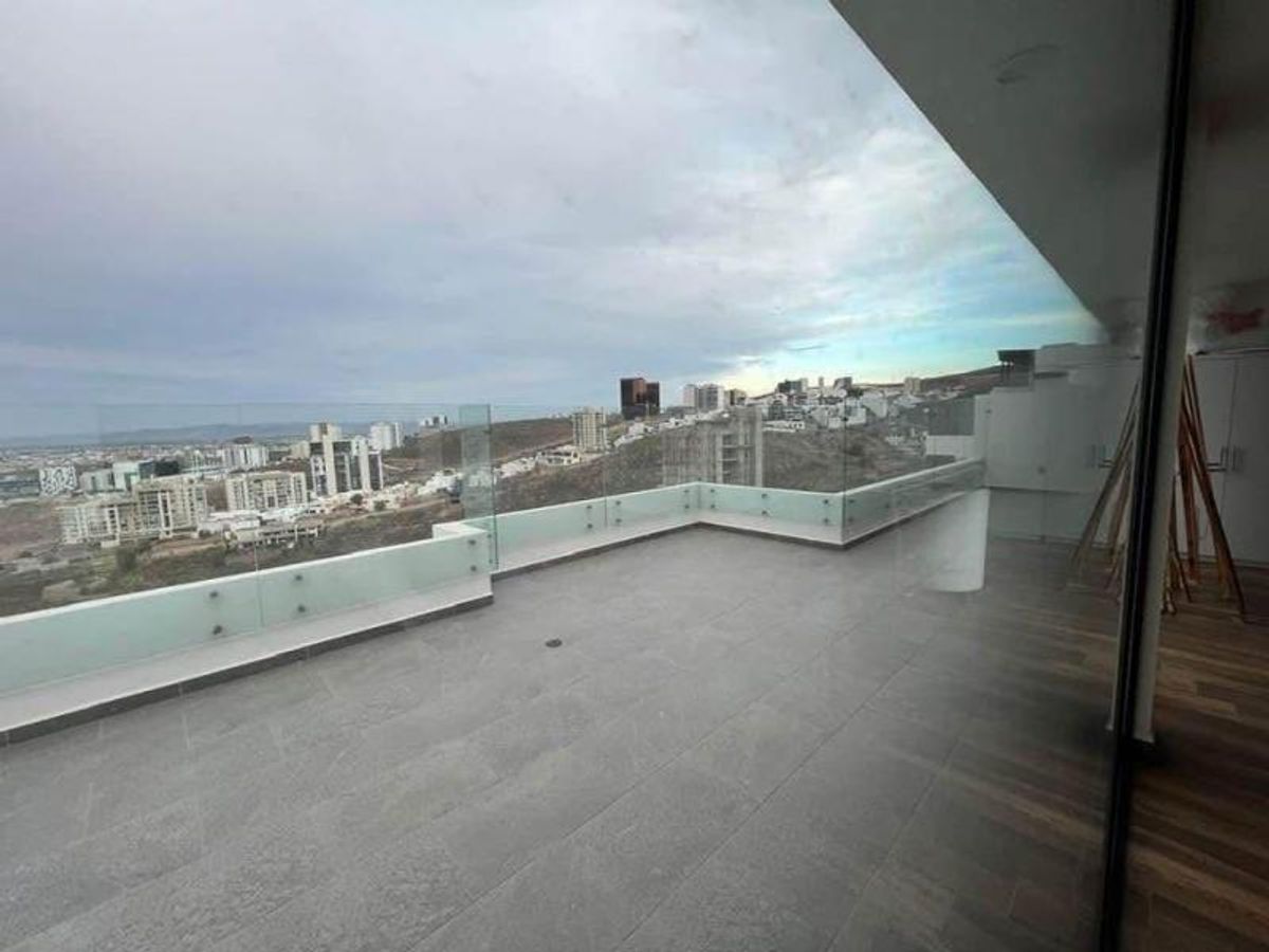 Terraza espaciosa con piso gris, barandal de vidrio y vista panorámica a la ciudad