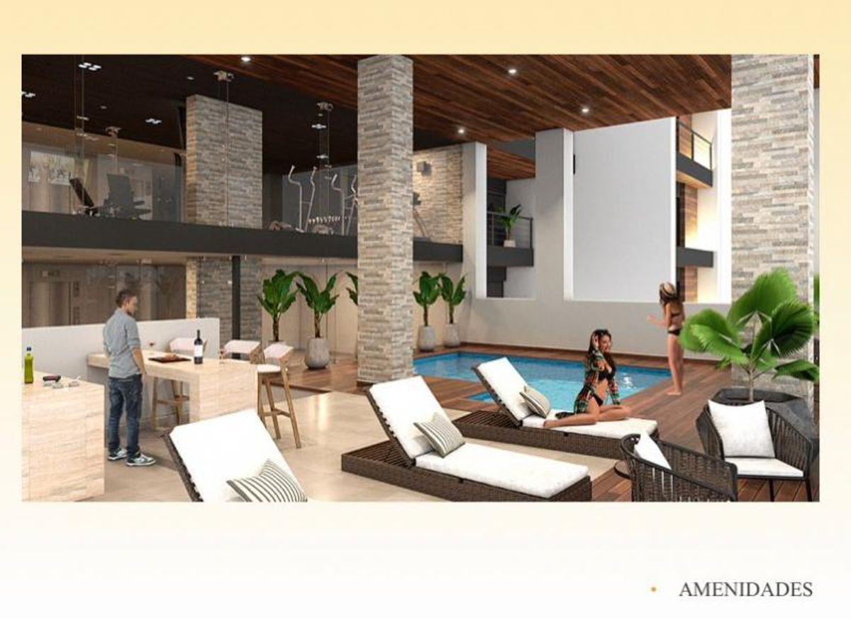 Alberca interior con camastros, columnas revestidas de piedra, barra y gimnasio en mezzanine