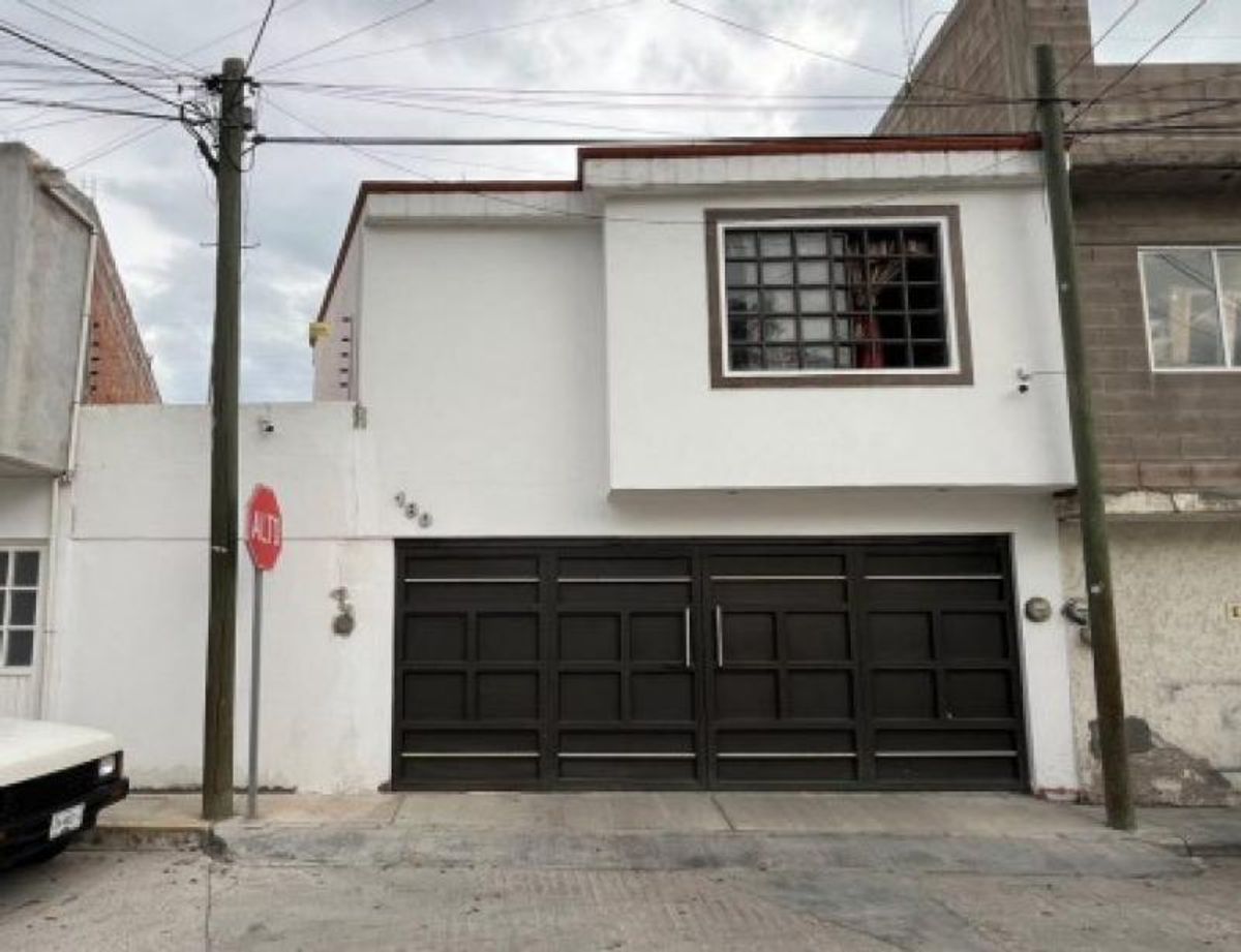 Fachada de casa blanca con portón metálico oscuro y ventana en planta alta