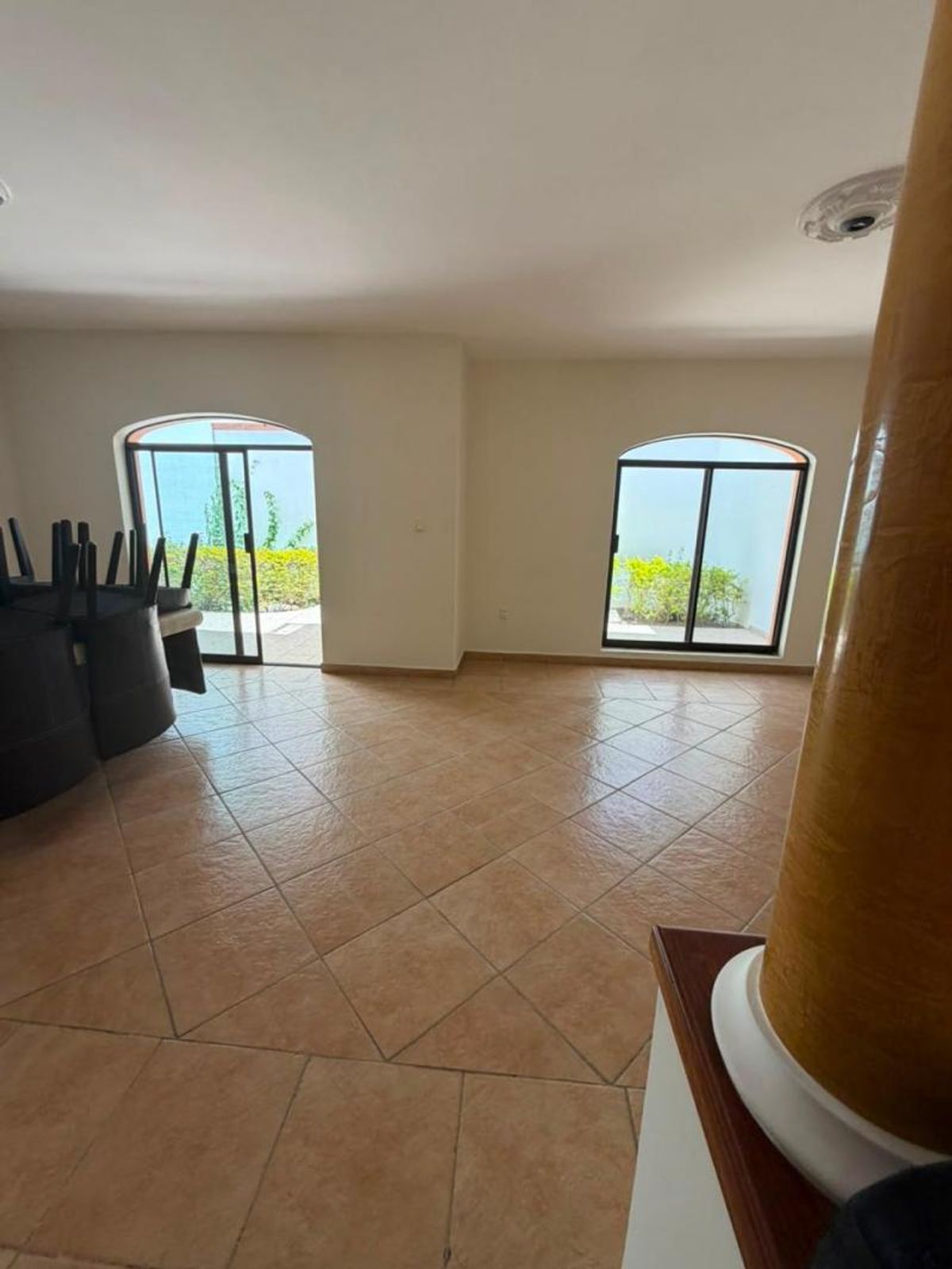 Espacio interior con piso de cerámica diagonal y ventanales arqueados hacia el jardín