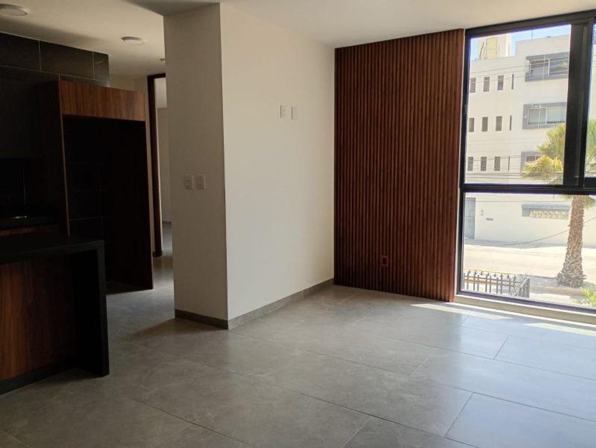 Sala con piso de porcelanato gris, pared revestida de madera y gran ventanal exterior