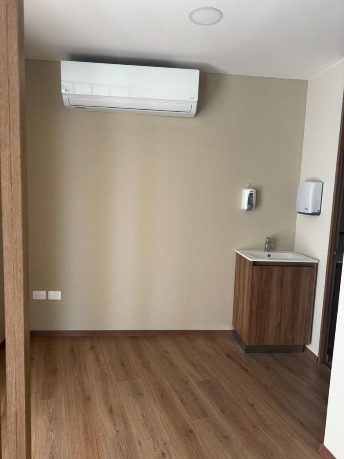Consultorio con piso de madera, aire acondicionado minisplit y lavamanos con mueble de madera