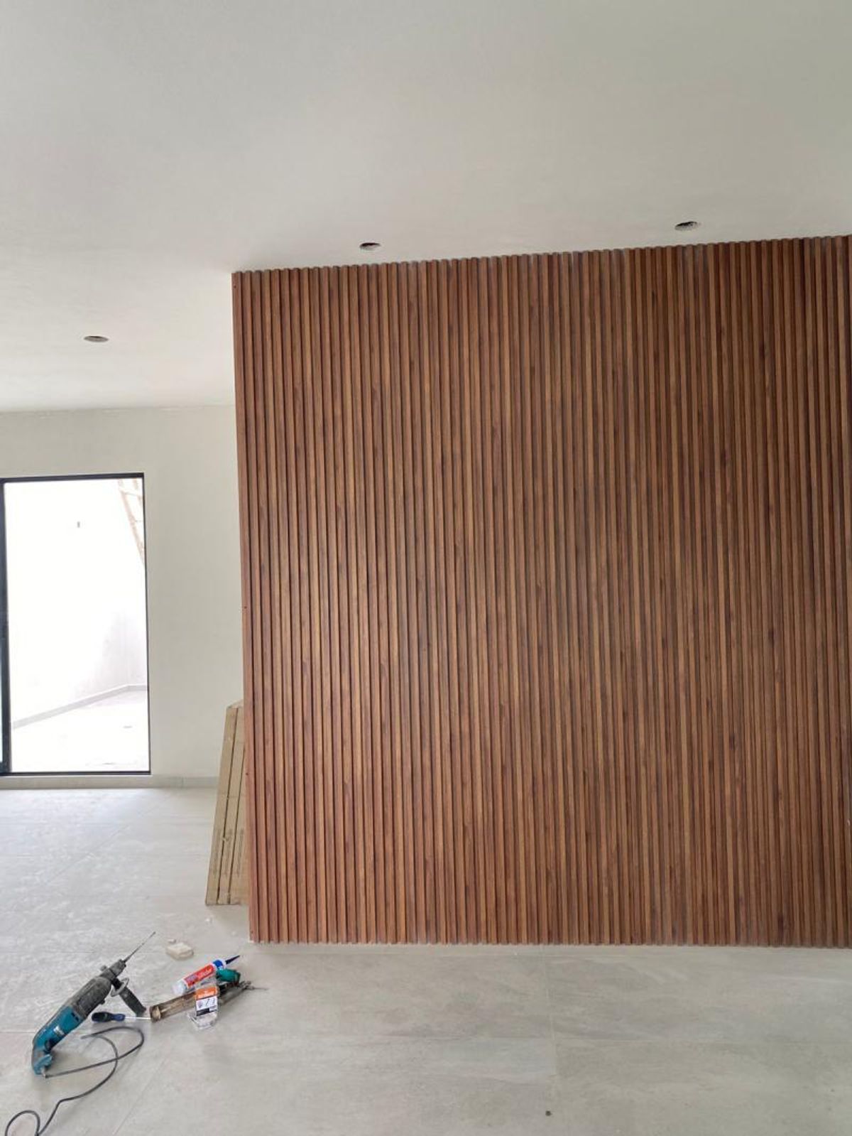 Muro interior revestido con listones verticales de madera y piso en tono claro
