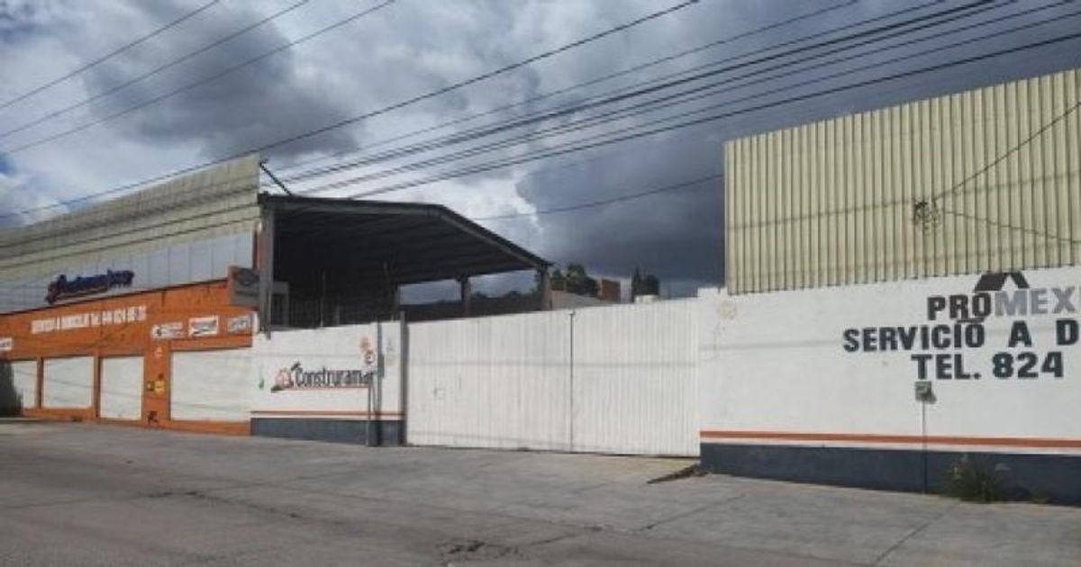 Exterior de bodega comercial con portón blanco, techado de lámina y frente pavimentado