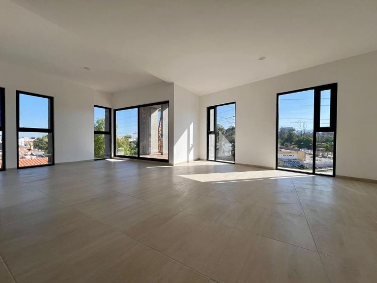 Espacio amplio con luz natural, piso de loseta clara y ventanales con marcos negros