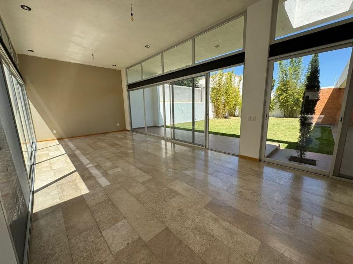 Estancia vacía con piso de mármol claro y grandes ventanales hacia el jardín