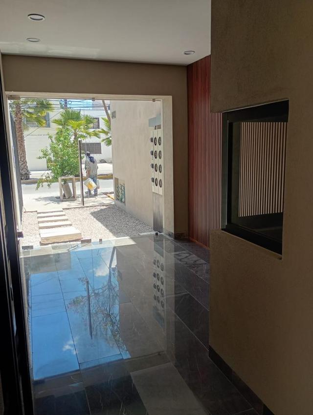 Acceso principal con piso brillante reflectante, ventanales de cristal y muro decorativo con listones