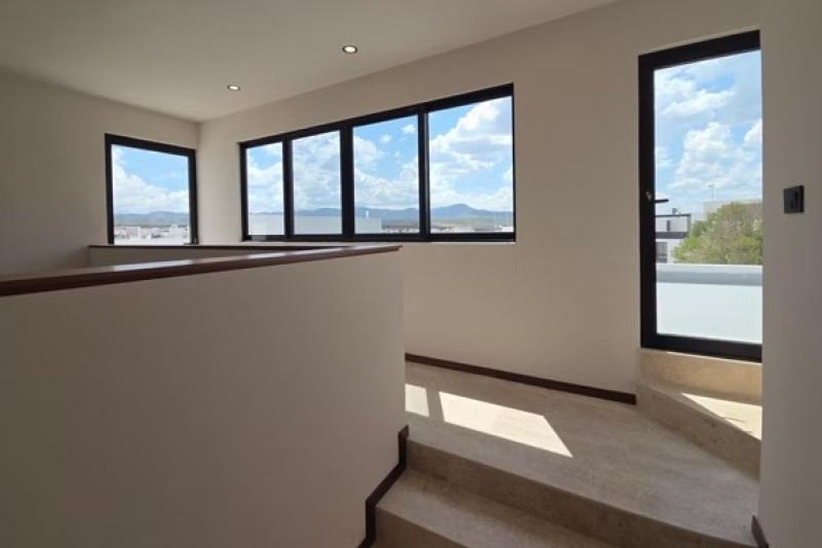 Vestíbulo con escalones de piedra clara, muro con remate de madera y ventanales negros