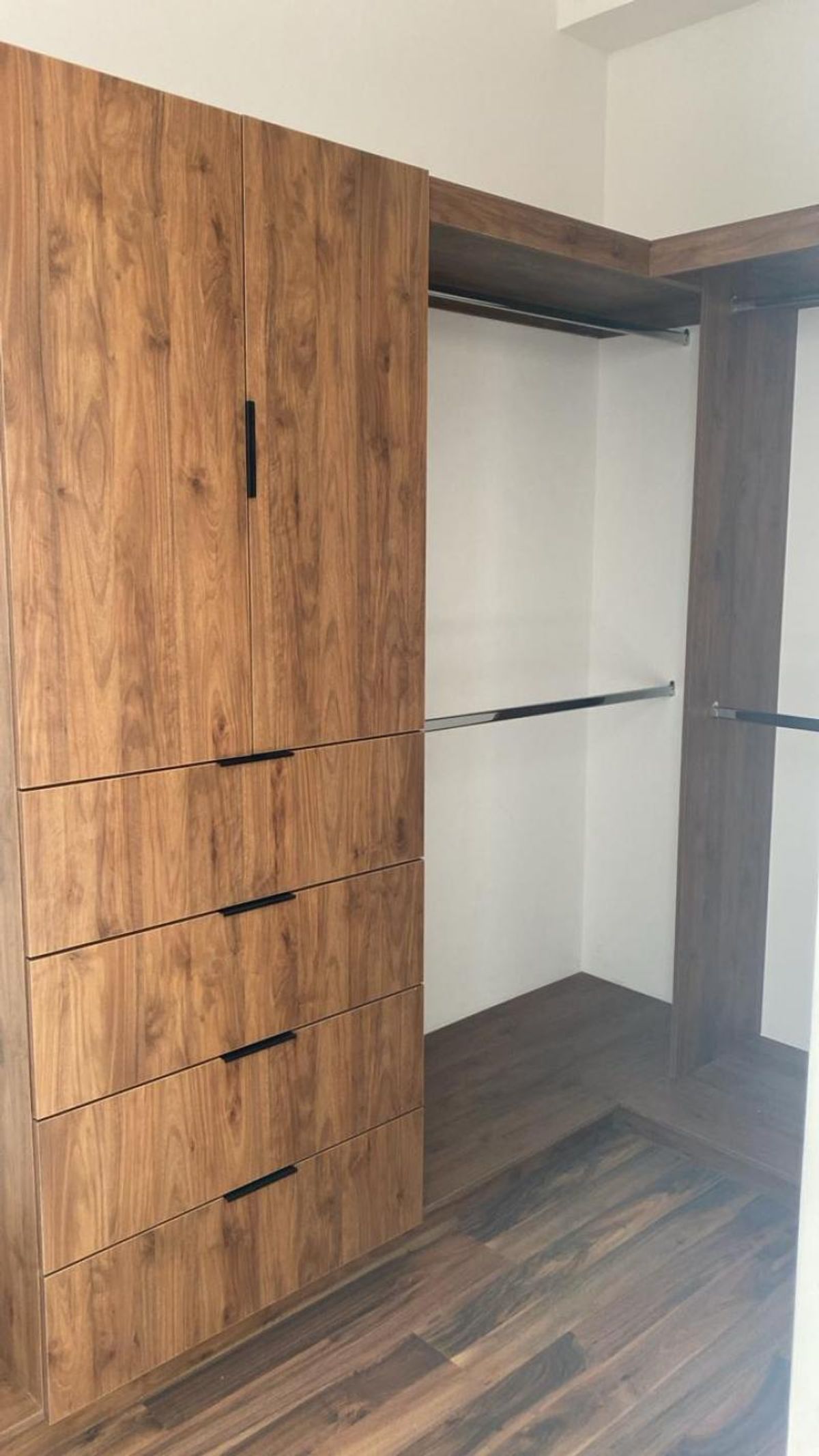 Vestidor de madera con cuatro cajones, gabinetes superiores y tubos metálicos para colgar