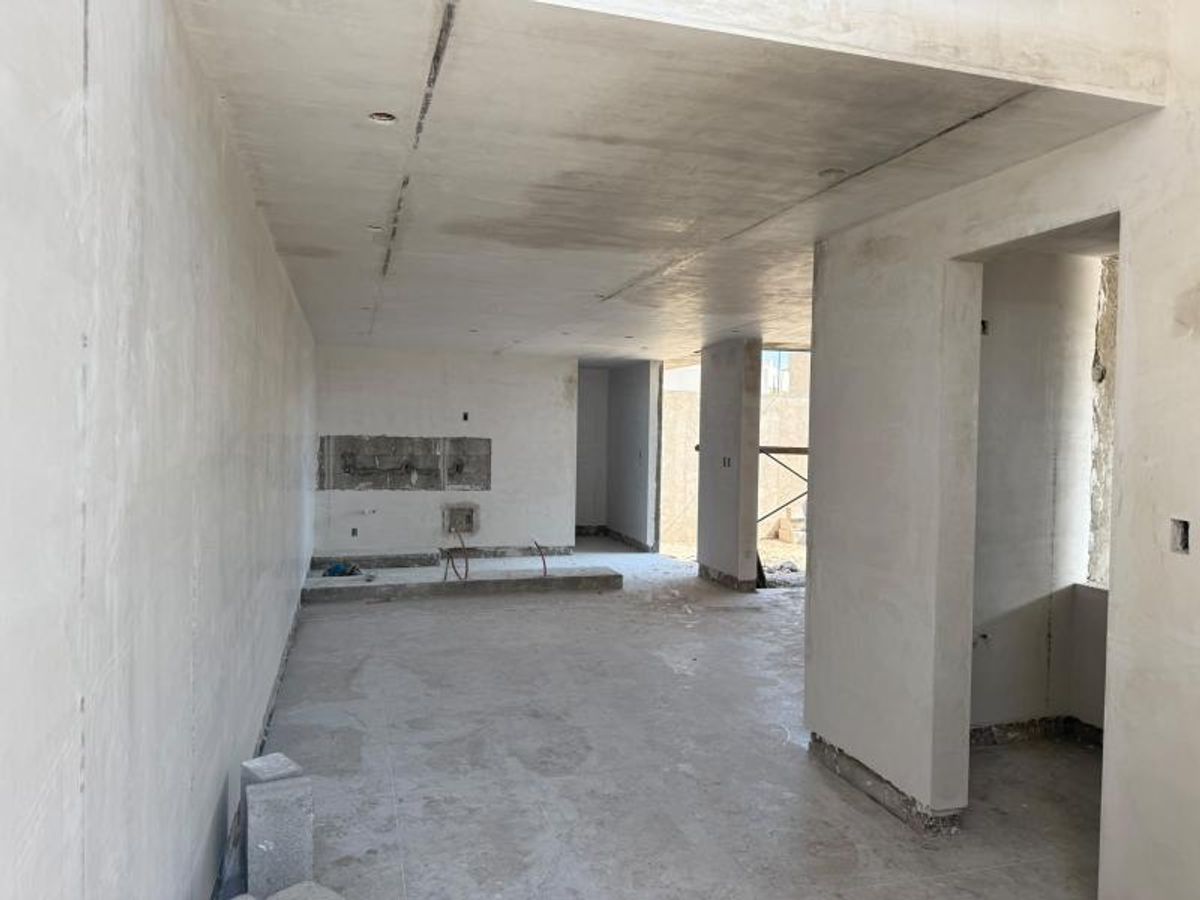 Interior en obra gris con muros repellados, piso de concreto y huecos para iluminación