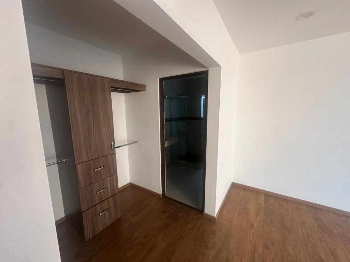 Vestidor de madera con cajonera, piso laminado y acceso a baño privado