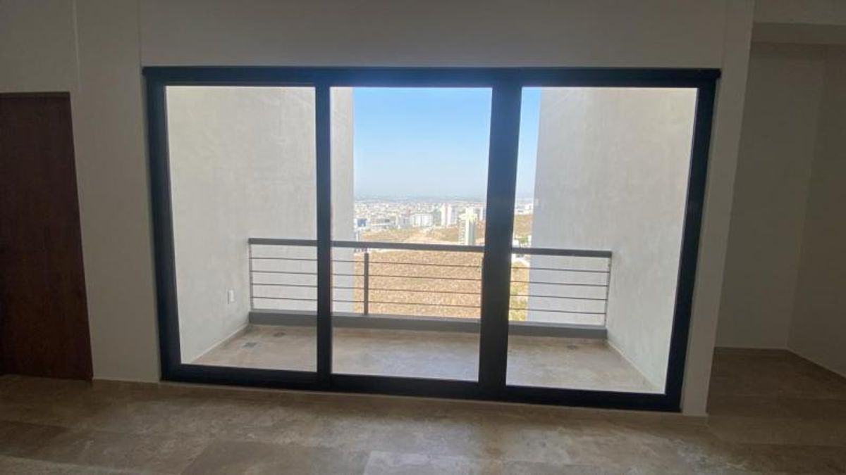 Ventanal con marco negro hacia balcón con barandilla metálica y vista panorámica de la ciudad