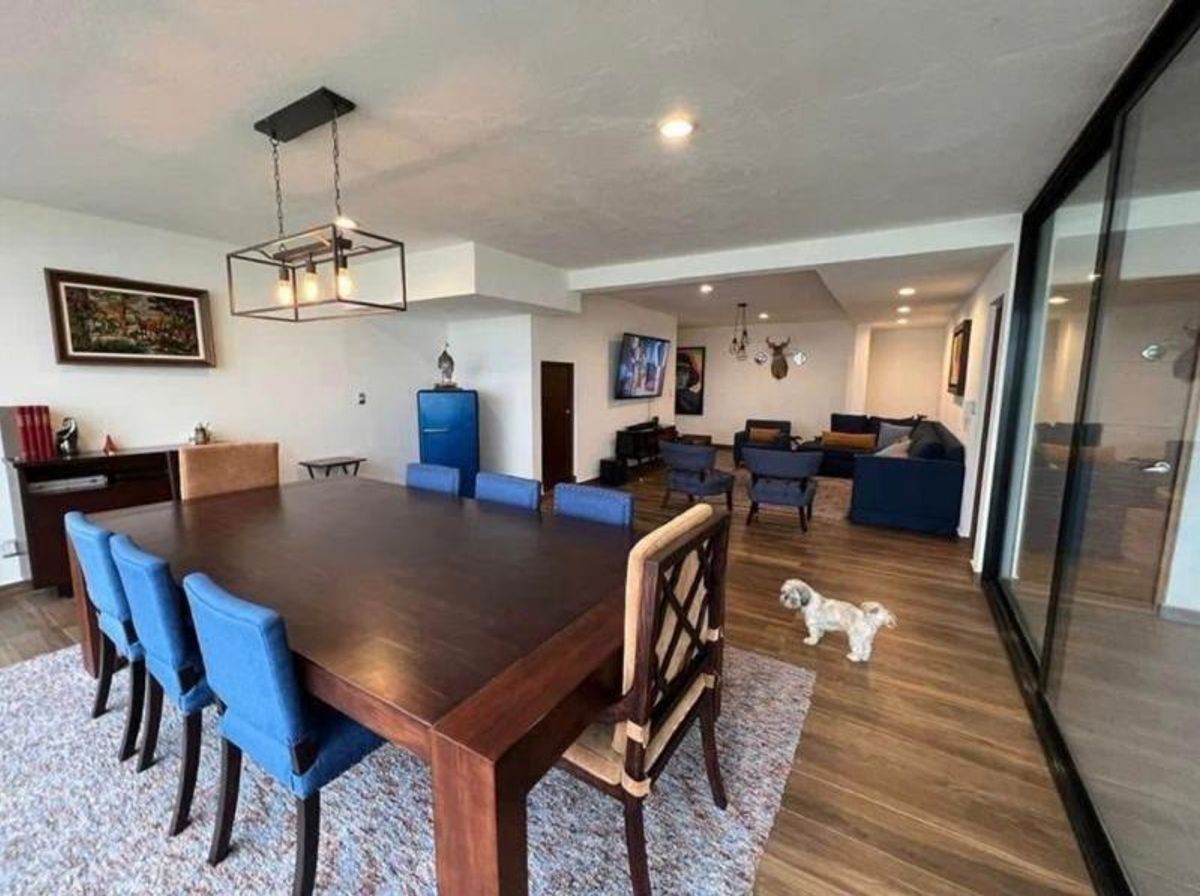 Comedor de madera oscura con sillas azules integrado a la sala de estar