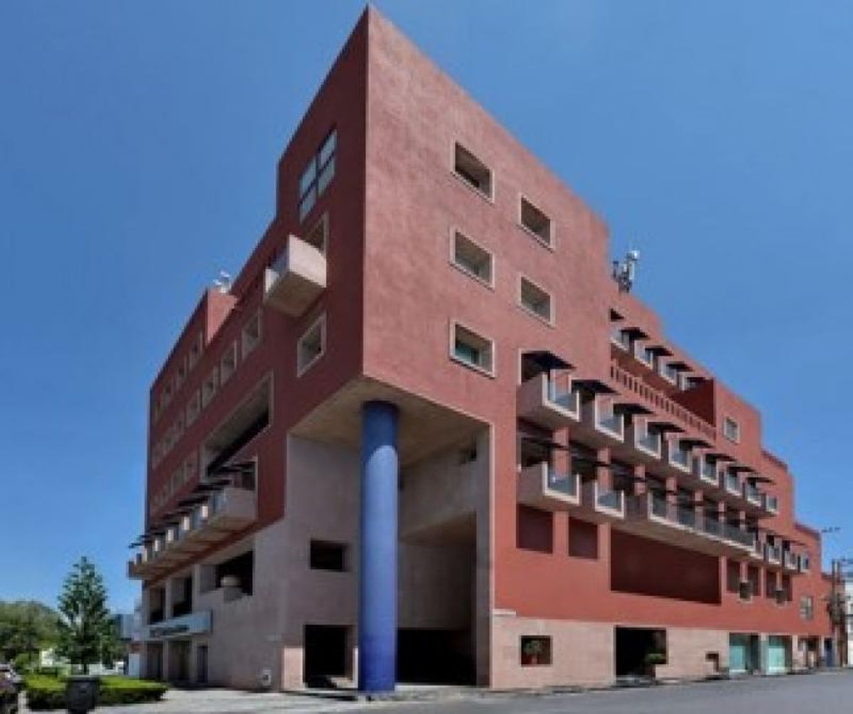 Edificio de fachada terracota con gran columna azul, múltiples balcones y ventanales rectangulares