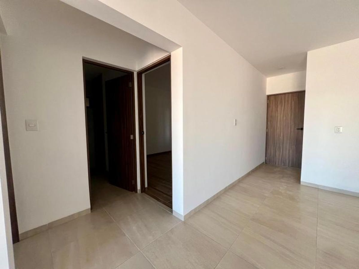 Pasillo interior con paredes blancas, piso de azulejo beige y puertas de madera oscura