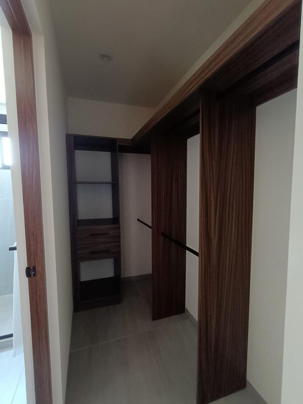 Vestidor de madera oscura con repisas, cajones, tubo para colgar y piso gris