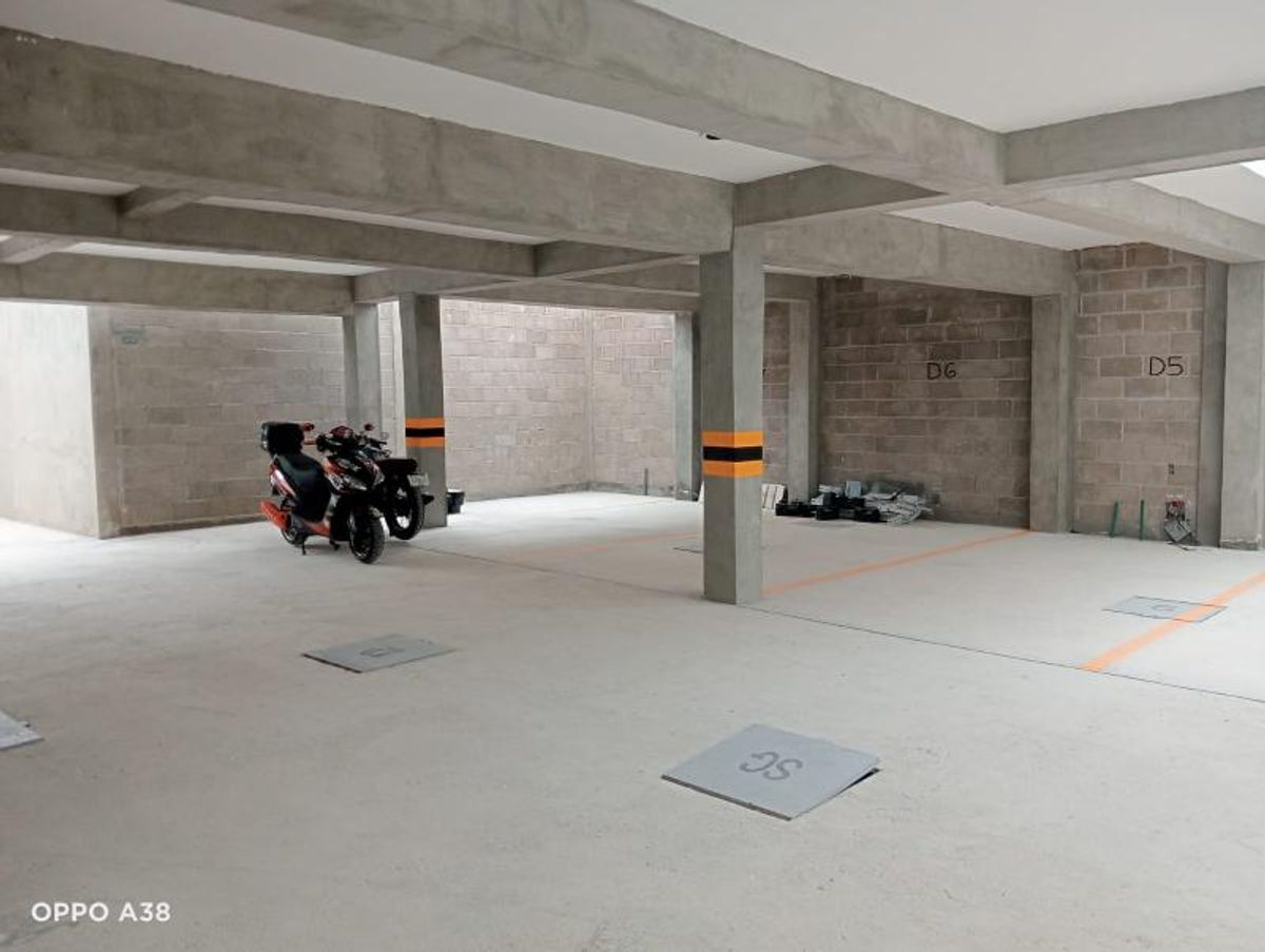 Estacionamiento techado con vigas y columnas de concreto, cajones marcados y muros de block