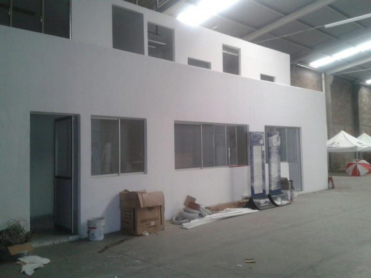 Interior de bodega industrial con oficina blanca de dos niveles y piso de concreto