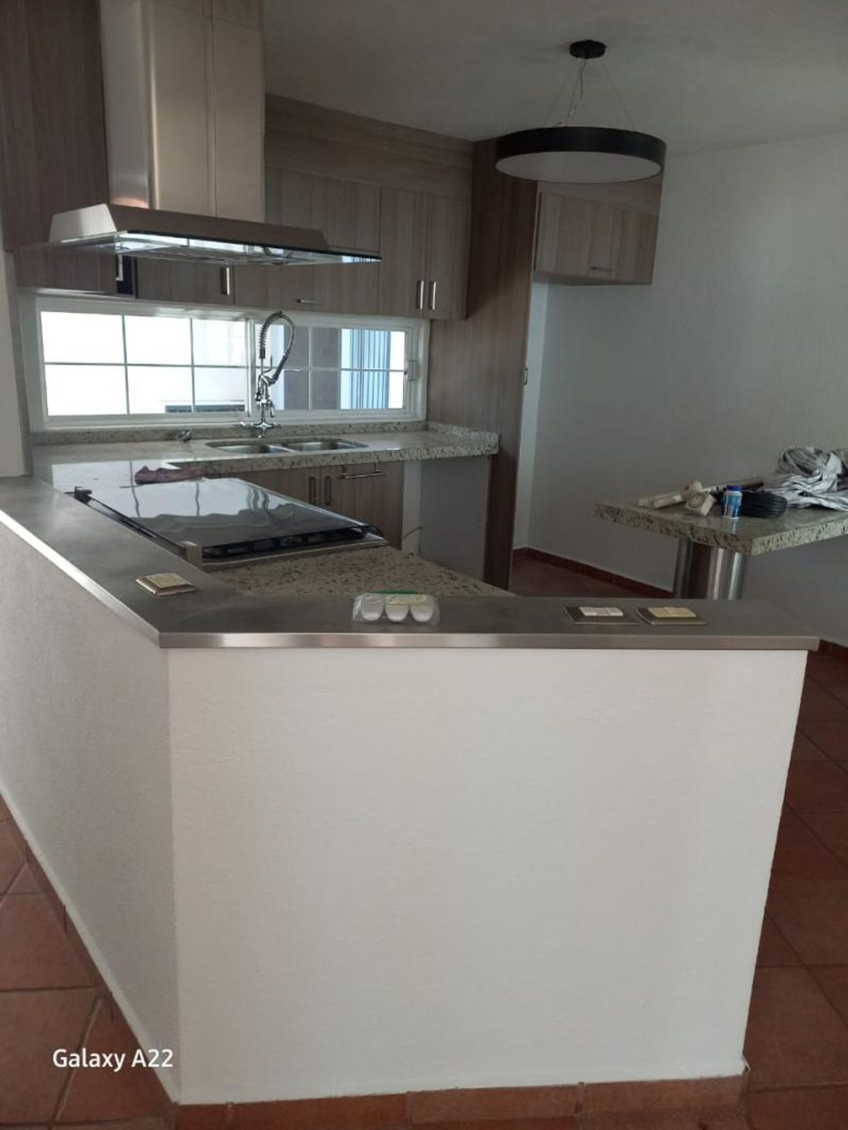 Cocina integral con campana de acero inoxidable, barra con estufa y gabinetes de madera