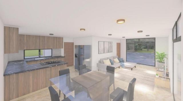Espacio abierto con cocina integral de madera, comedor de cristal y sala con ventanal