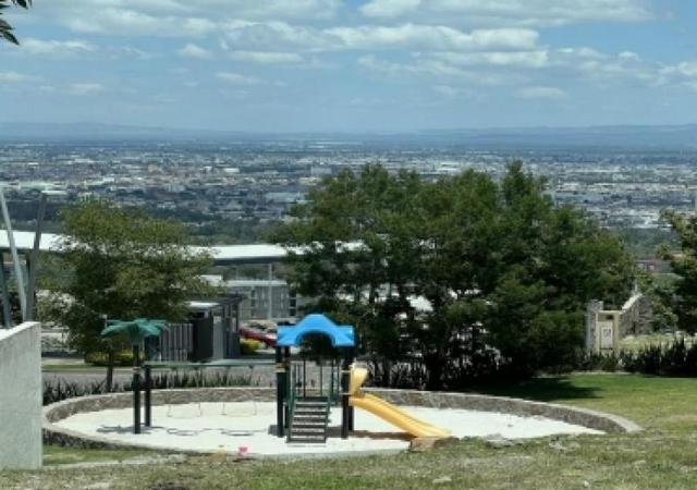 Área de juegos infantiles con resbaladilla amarilla y vista panorámica a la ciudad