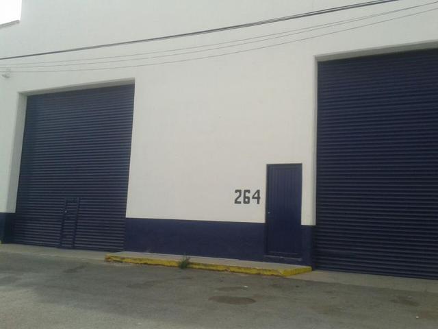 Fachada blanca y azul con dos cortinas metálicas enrollables, puerta peatonal y número 264