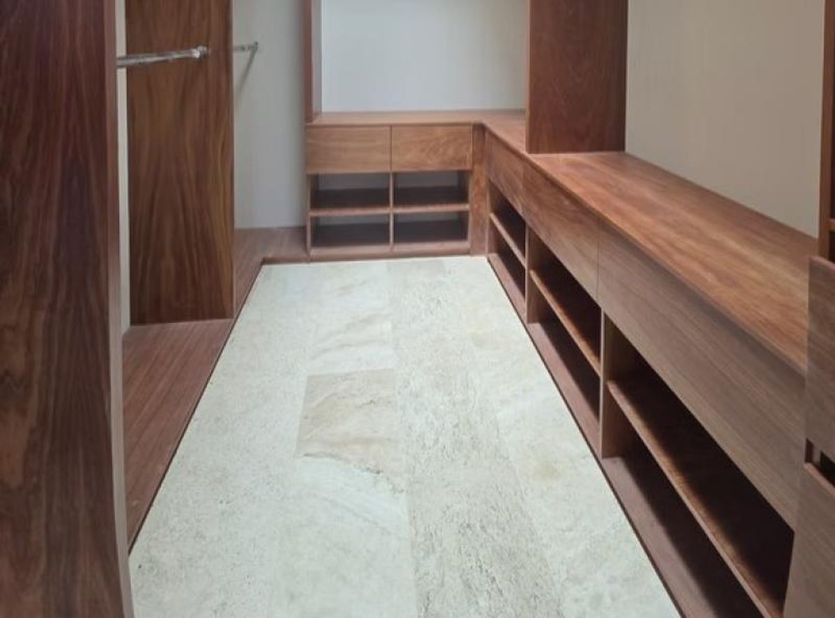 Vestidor con muebles integrados de madera oscura, cajones, repisas y piso de mármol claro