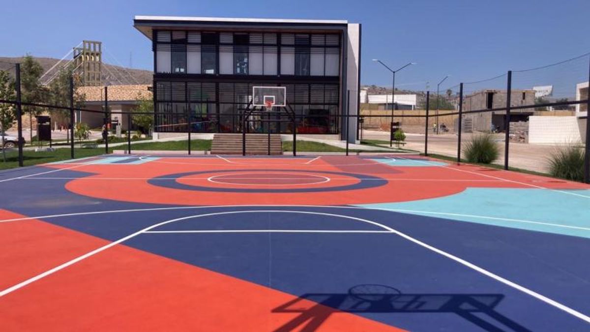 Cancha de básquetbol al aire libre pintada de colores frente a edificio moderno