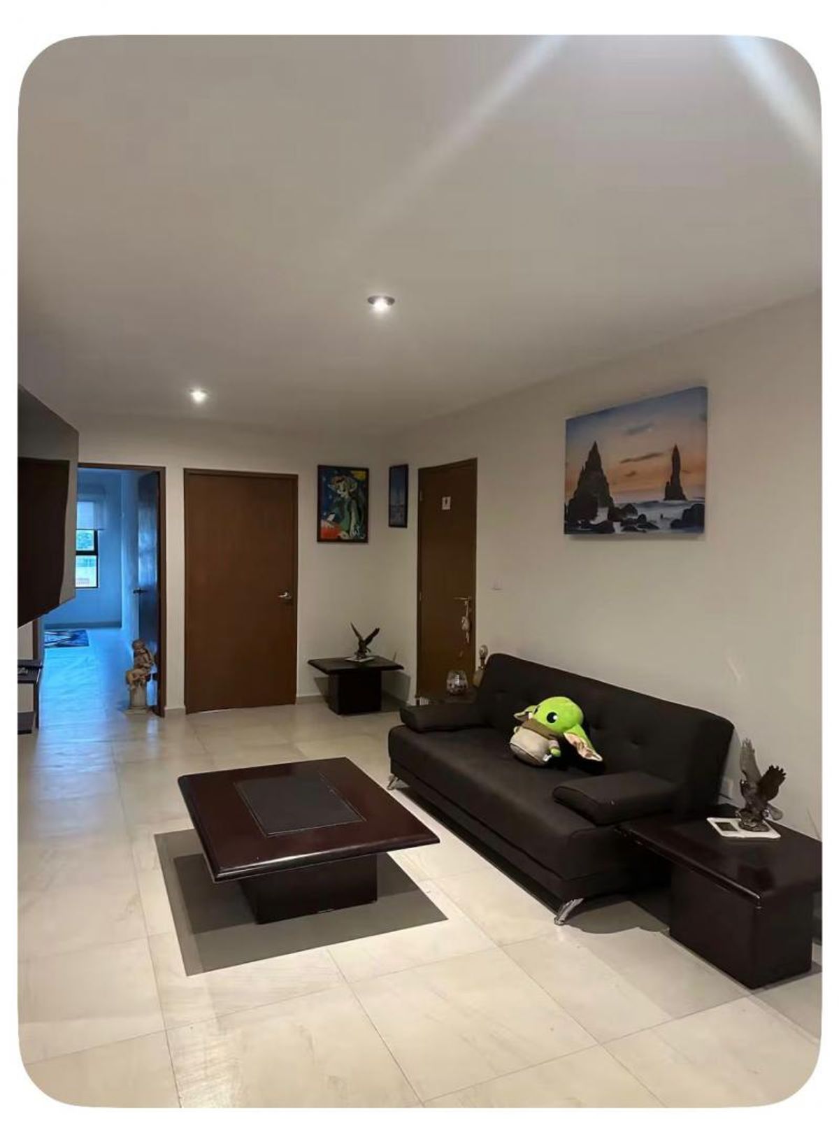 Sala de estar con sofá oscuro, mesa de centro de madera y piso claro