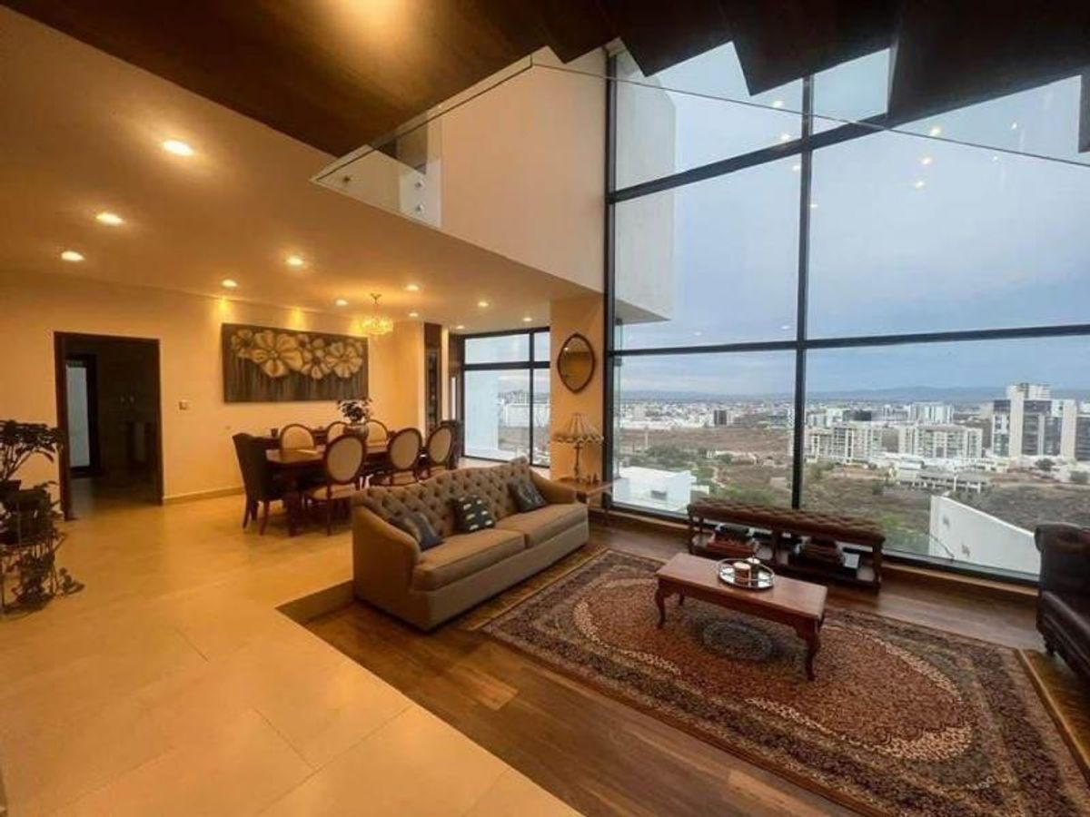 Sala con ventanales de piso a techo, comedor al fondo y vista panorámica urbana