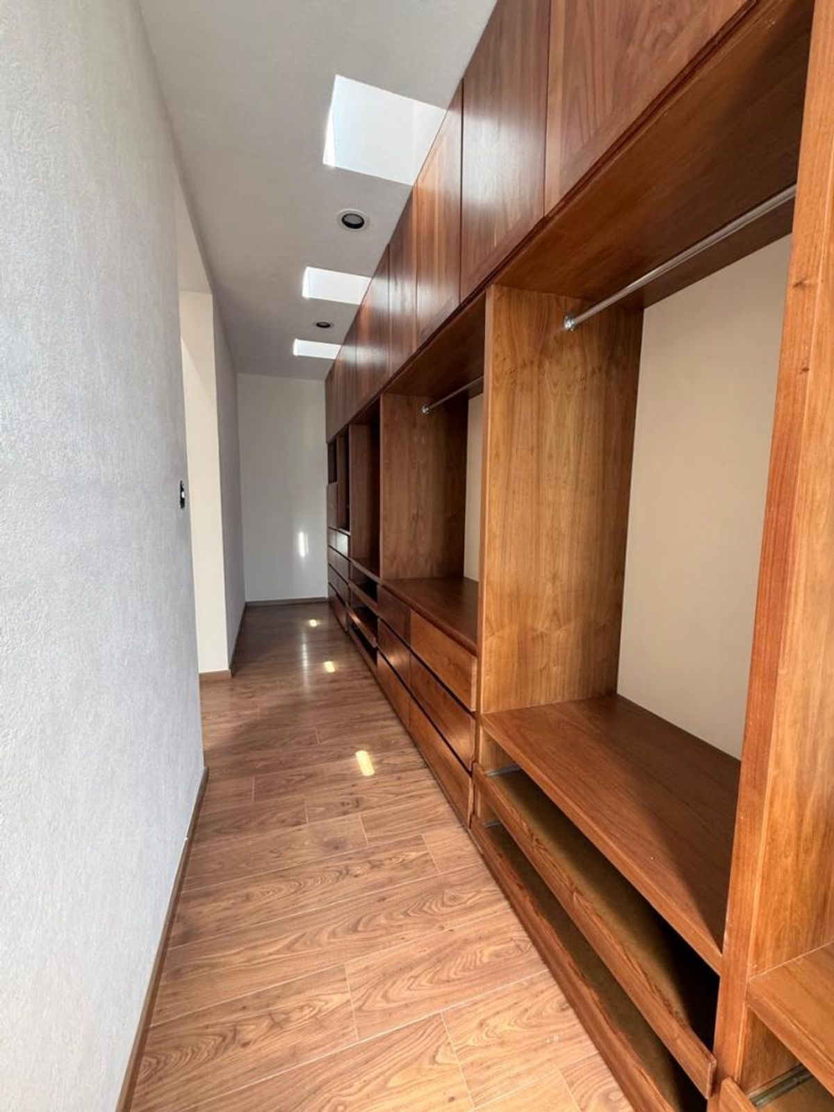 Vestidor de madera con cajones, repisas, barras para colgar ropa y piso de madera
