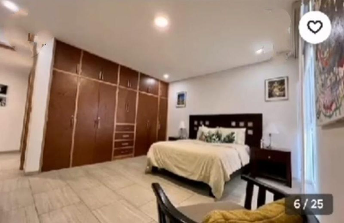 Recámara con closet de madera empotrado, cama matrimonial con cabecera oscura y piso claro