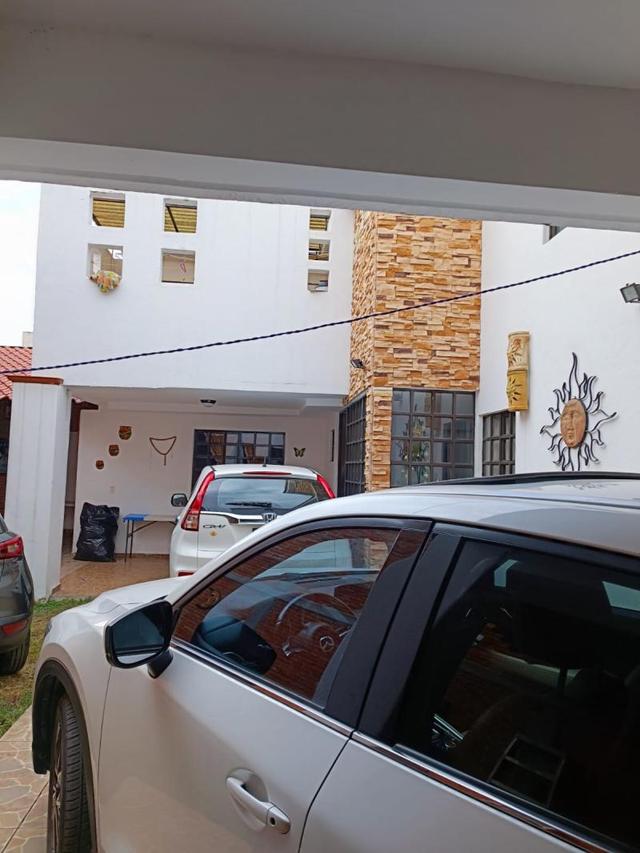 Fachada de casa blanca con revestimiento de piedra y cochera techada con vehículos