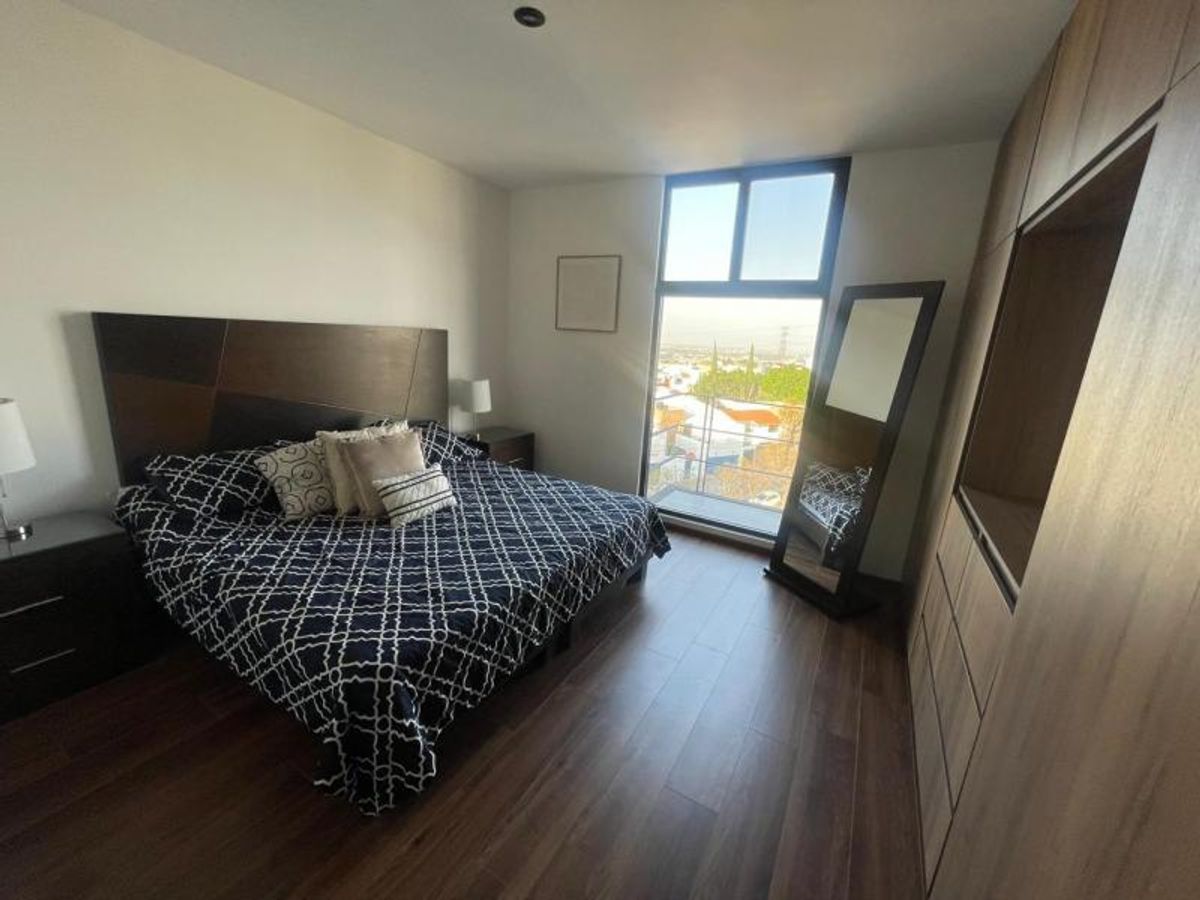 Recámara con piso de madera, cama con cabecera oscura, clóset integrado y ventanal exterior
