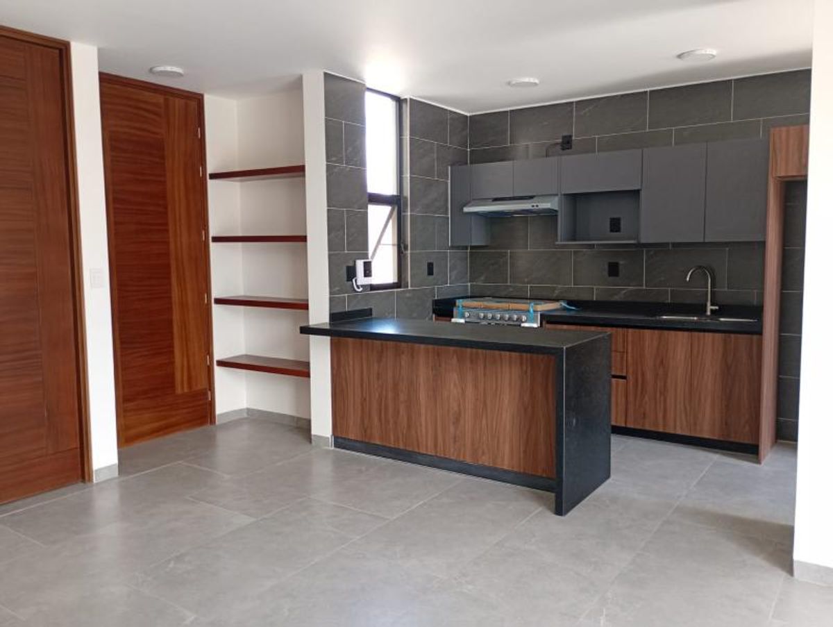 Cocina con barra de madera, gabinetes superiores grises, repisas flotantes y piso gris claro