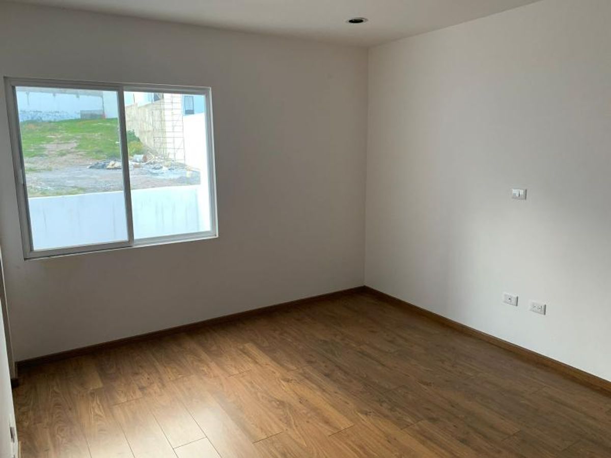 Habitación vacía con piso de madera, paredes blancas y ventana con vista al exterior