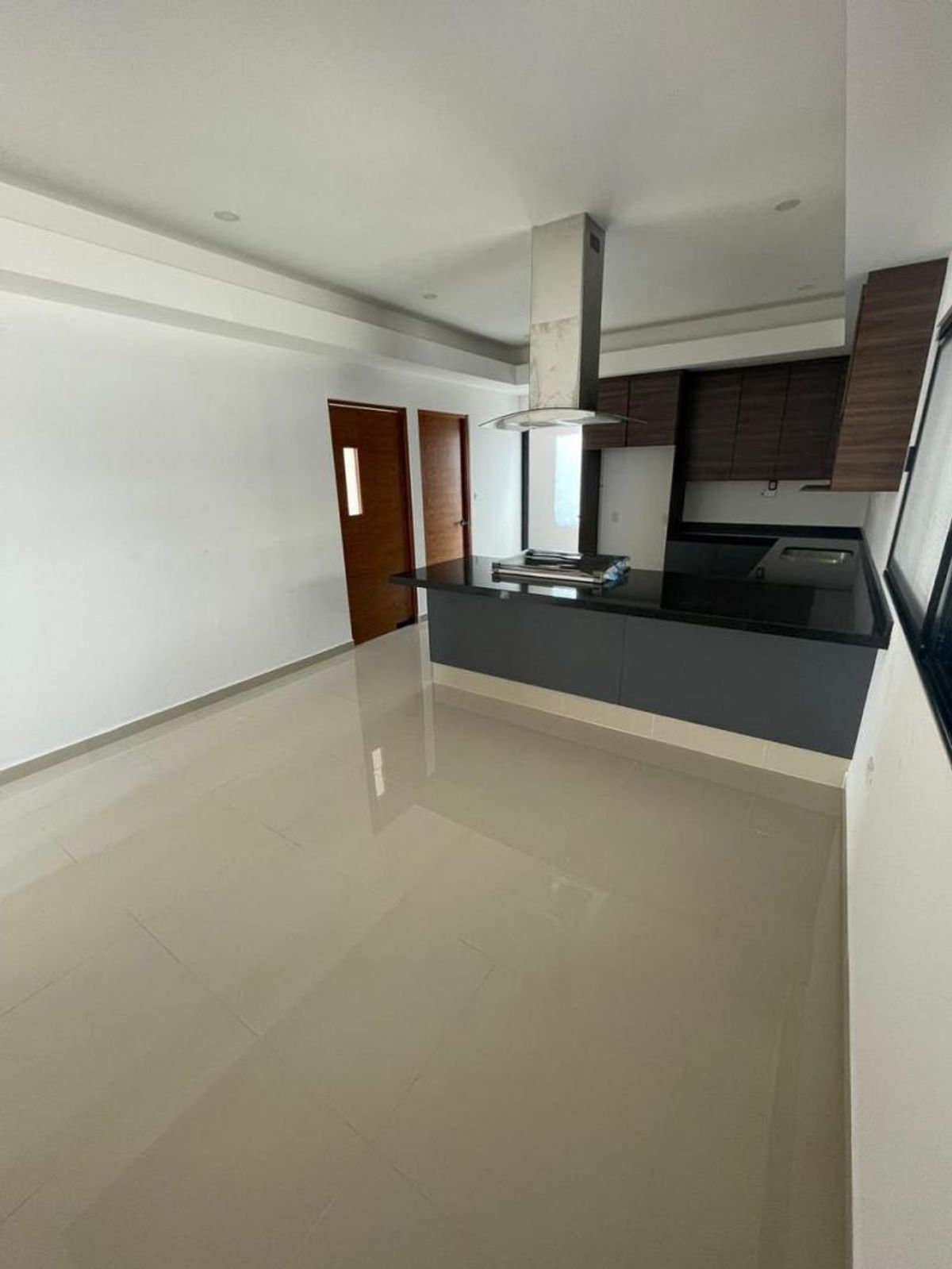 Cocina con barra de cubierta oscura, campana de acero inoxidable, gabinetes y piso brillante